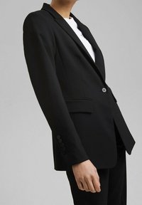 Czarna, dopasowana marynarka o smukłym kroju, z pojedynczym zapięciem na guzik, klapami i dwoma przednimi kieszeniami; gładki materiał, minimalne detale.