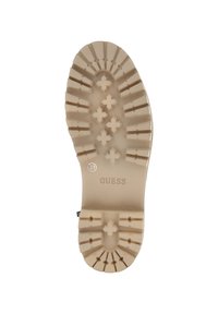 Beżowa gumowa podeszwa buta z teksturowanym wzorem w rygi i krzyże, z wytłoczonym logo marki "GUESS" oraz rozmiarem "37".