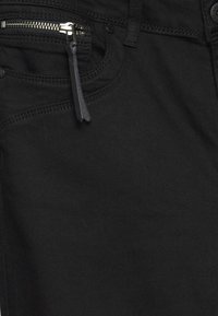 Jeans de mezclilla negra con un bolsillo con cremallera y un tirador de cuero, costuras prominentes y un acabado de textura suave.