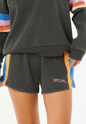 Osoba ubrana w ciemnoszare spodenki Rip Curl z niebieskimi i pomarańczowymi paskami po bokach oraz pasującą ciemnoszarą bluzę z kolorowymi paskowanymi rękawami.