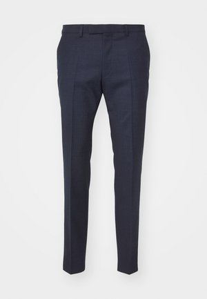 Costume marine avec une coupe structurée, veste ajustée et pantalons sur mesure. Associé à une chemise blanche et des chaussures marron foncé. Texture de tissu lisse.