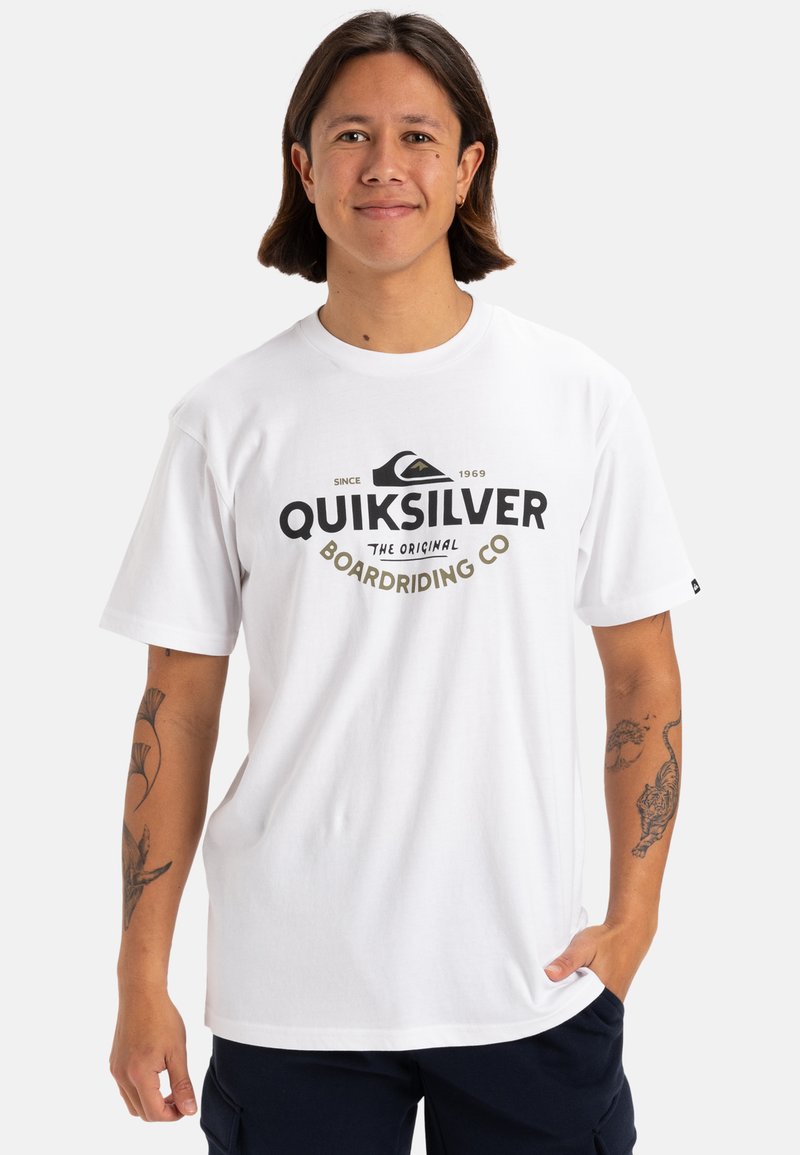 Camiseta de algodón blanca con un logotipo negro de Quiksilver y elementos de diseño. Mangas cortas y estilo de cuello redondo. Textura suave, ajuste casual.