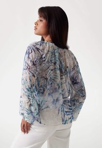 Bluză transparentă cu modele florale albastre și accente brodate albe. Mâneci lungi, ușor bufante. material ușor și croială lejeră.