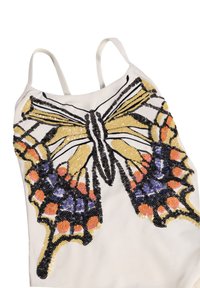 Λευκό τοπάκι με λεπτές τιράντες, διακοσμημένο με έναν μεγάλο, πολύχρωμο σχεδιασμό πεταλούδας από παγιέτες σε κίτρινο, πορτοκαλί, μαύρο και μωβ.