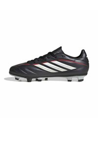 Chaussure de football noire avec des bandes blanches Adidas, des accents rouges, des lacets, et des crampons moulés sur la semelle pour jouer sur terrain ferme.