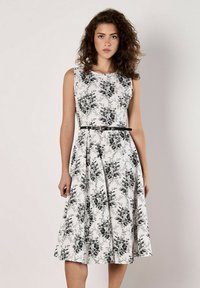 Vestido floral en blanco con patrones de rosas negras, diseño sin mangas, corsé ajustado, falda acampanada y un cinturón negro en la cintura.
