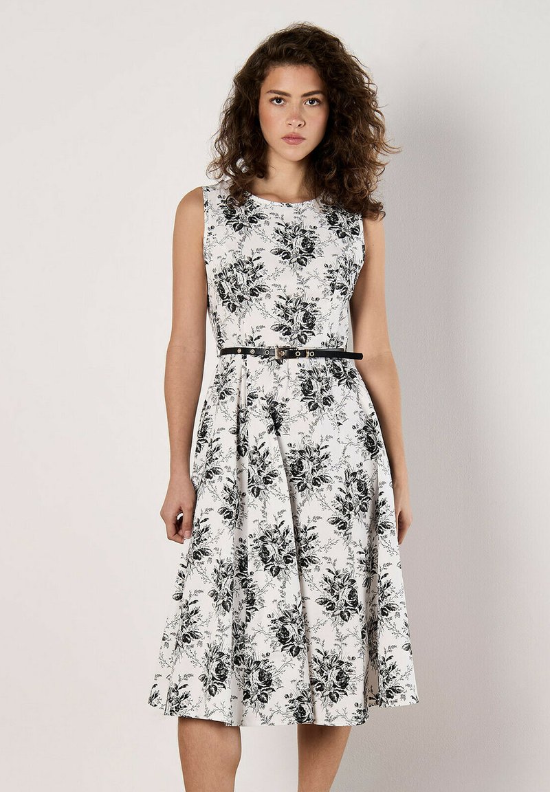 Vestido floral en blanco con patrones de rosas negras, diseño sin mangas, corsé ajustado, falda acampanada y un cinturón negro en la cintura.