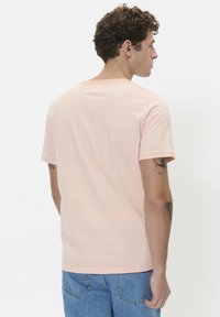 Short-sleeve, crew-neck T-shirt in light peach with thin white stripes. Soft cotton fabric with a relaxed fit and plain back design.