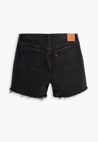 Shorts en denim noir avec ourlets effilochés, deux poches arrière, une étiquette en tissu rouge sur la poche droite et un patch de marque en cuir marron sur la ceinture.