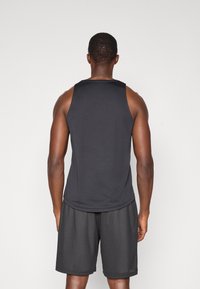 Schwarzes ärmelloses Sporttanktop mit glatter Textur; kombiniert mit schwarzen Mesh-Shorts, die einen lockeren Schnitt und ein atmungsaktives Design aufweisen.