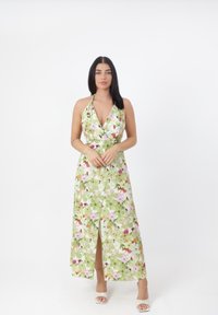 Maxikjole med halterneck, prydet med et blomstermønster i grønne, pinke og lilla nuancer, samt en høj slids. Glat, let stof.