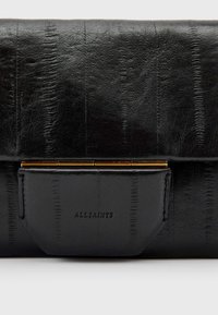 Clutch in pelle nera con superficie texturizzata e hardware color oro. Presenta un flap piegato e il logo "ALLSAINTS" in rilievo.