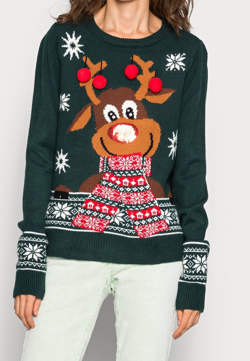 Pull tricot vert avec un motif de renne, des accents rouges, des pompons et des motifs de flocons de neige. Poignets côtelés avec des détails blancs.