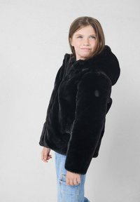 Chaqueta negra de piel sintética con capucha, con un corte relajado, mangas largas y textura suave. Combinada con jeans de mezclilla azul claro.