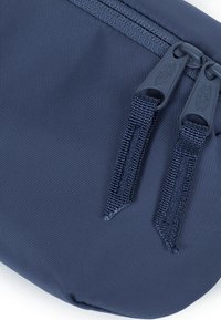 Pochette blu navy realizzata in tessuto testurizzato, dotata di doppie cerniere con linguette in tessuto e cucitura rinforzata, ideale per accessori o cavi.