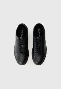 Adidași din piele neagră cu o textură netedă, având vârf rotund, șireturi plate și logo pe branț. Design minimal.