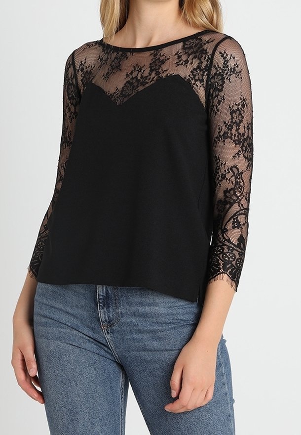 Top nero con maniche lunghe in pizzo trasparente con motivi floreali e corpino nero solido. Collo rotondo, vestibilità rilassata e texture morbida.