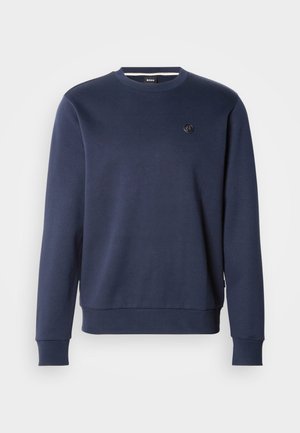 Marineblauwe katoenen trui met een ronde hals, geribbelde manchetten en zoom. Heeft een klein logodetail op de borst.