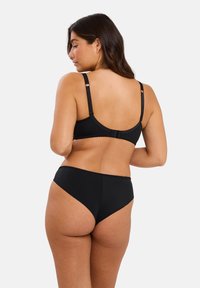 Ensemble de lingerie noir comprenant un matériau lisse et extensible avec des bords festonnés, des bretelles réglables et un design classique.