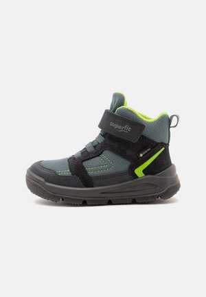 Παιδικό sneaker ψηλού τύπου σε γκρι και μαύρο με νέον πράσινες λεπτομέρειες, λουράκι με βέλκρο και ανθεκτική μαύρη σόλα, σχεδιασμένο για υπαίθρια χρήση.