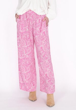 Růžové kalhoty s paisley vzorem a širokými nohavicemi, s elastickým pasem a bočními kapsami, doplněné béžovými kotníkovými botami. Měkká, lehká látka.