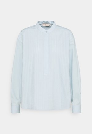 Lyseblå bluse med lange ærmer, verticale plisser foran, ståkrave med enkelt knap og skjult knapstolpe.