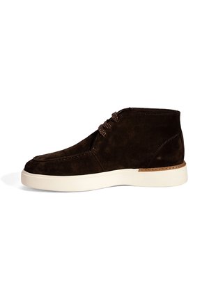 Dunkelbrauner Wildleder-Ankle-Boot mit weißer Sohle und braunen Schnürsenkeln, seitlich auf einem weißen Hintergrund abgebildet.