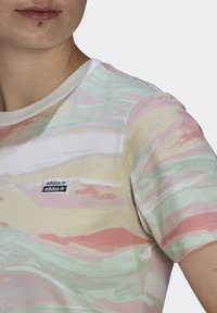 Krátký rukáv tričko v pastelových barvách se vlnovým vzorem. Vyrobeno z měkké tkaniny s kulatým výstřihem a malým logem Adidas.