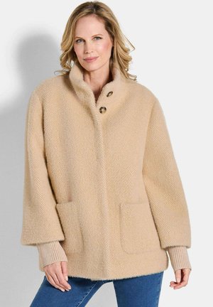 Beige wollen blended jas met een visgraatpatroon, hoge kraag, twee voorzakken en geribde manchetten. Ontworpen met een ontspannen pasvorm en moderne silhouet.