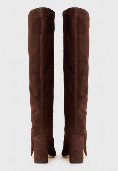 Stivali in suede marrone alti fino alla coscia, con una texture liscia, tacchi quadrati e un design aderente. La parte posteriore presenta un delicato dettaglio di cucitura.
