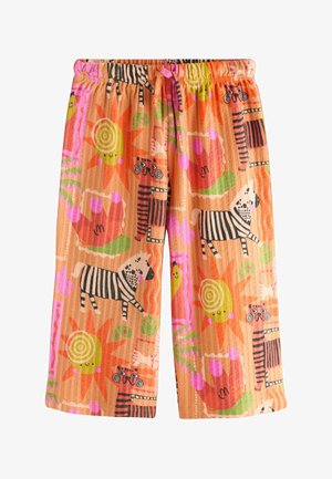 Pantaloni arancioni per bambini con vita elastica, caratterizzati da stampe colorate di soli sorridenti, zebre, tigri striate, foglie e forme astratte.