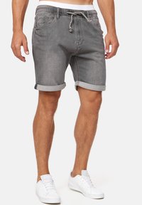 Shorts en denim gris avec des ourlets roulés, taille élastique et cordon de serrage. Comprend des poches avant et une texture lisse.