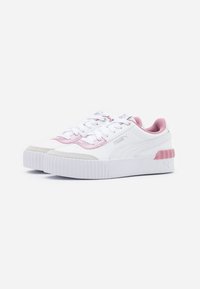 Baskets Puma blanches à tige basse avec des accents roses, semelles épaisses à nervures et lacets, présentées sous un angle avant sur un fond blanc.
