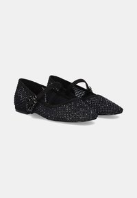 Zapatos planos negros con punta afilada, decorados con una textura trenzada y pequeños remaches, que cuentan con una correa entrelazada y un tacón mínimo.