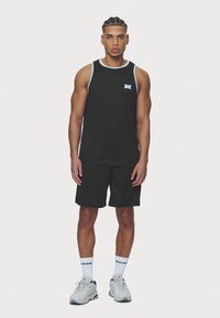 Crna bezrukavna sportska majica s svijetloplavim obrubom, uparen s crnim kratkim hlačama. Nosi se s sivim tenisicama i bijelim čarapama s logotipom.