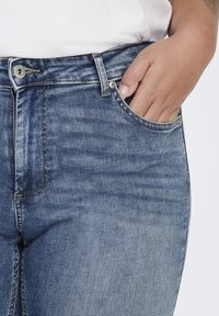Jeans de denim en un lavado azul claro, que cuentan con un bolsillo frontal y costuras visibles. La tela tiene una textura ligeramente desgastada.