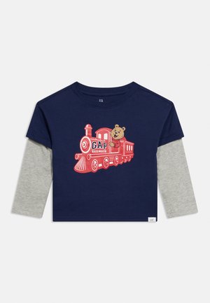 Chemise à manches longues pour tout-petit bleu marine et grise avec un motif de train rouge et un personnage d'ours faisant signe depuis la fenêtre du train.