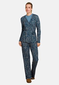 Langärmlige Wickeloberteil und passende Hose in Marineblau mit Blumenmuster. Leichte Stoff, Taillengürtel und lockere Passform. Bequeme Fußbekleidung inklusive.