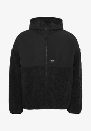 Juoda kapučiuko striukė su minkštu, tekstūruotu fliso apatine dalimi, lygiu viršutiniu audiniu, priekiniais užtrauktukais ir mažu logotipo ženkleliu ant krūtinės.