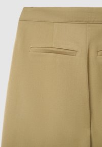Pantaloni khaki con tessuto liscio e testurizzato. Presentano due tasche posteriori con alette sottili e un design pulito e sartoriale.