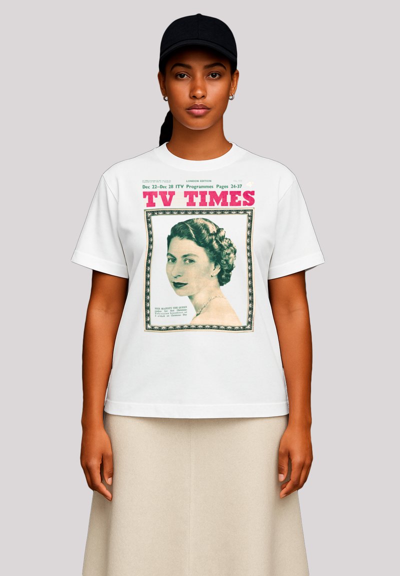 Woman wearing a black cap, white t-shirt with vintage "TV Times" magazine cover featuring a portrait of a woman with styled hair and a necklace.