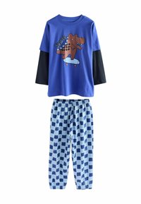 Blauwe pyjama set met een T-shirt met korte mouwen met een graphics van een skateboardende dinosaurus en lange zwarte mouwen; blauwe geruite pyjamabroek.