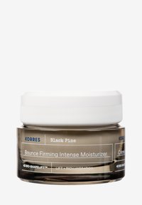 Rund glasburk med en frostad brun finish, vit skruvkapsyl och blå text; märkt som "KORRES Black Pine Bounce Firming Intense Moisturizer."