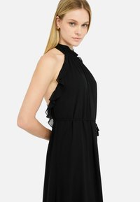 Crna halter haljina s naboranim detaljima, plisiranim teksturom i elastičnom strukom za prilagođeni kroj. Glatka tkanina teče elegantno.