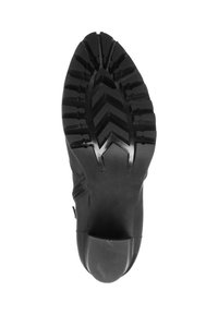 Suela de zapato deportivo negra con un diseño robusto que presenta un prominente patrón de zigzag para tracción y agarre. Material de goma suave y duradera.