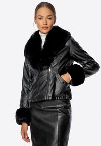 Černá kožená bunda se širokým umělým kožichem na límci a manžetách. Zapínání na zip, šikmé kapsy a střih na míru. Hladká textura, přiléhavý tvar.