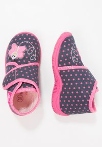 Dark blue fabric shoes with pink polka dots, pink soles, and a floral design with embroidery. Closed-toe with a Velcro strap.