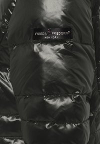 Czarna kurtka puchowa z błyszczącego materiału, z pikowanymi sekcjami i czarną metką z napisem "FRIEDA FREDDIES NEW YORK."
