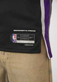 Juodas krepšinio marškinėliai su violetiniais ir baltais akcentais, su užrašu "SACRAMENTO PROUD" ir Nike etikete, nurodančia 44 dydį.