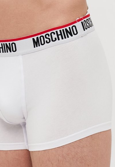 White cotton boxer briefs featuring a contrasting black and red Moschino logo waistband, smooth texture, and fitted design.
